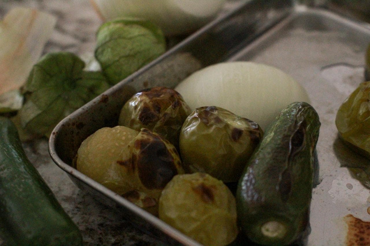 Edited close-up of roasted tomatillos on sheet pan for blog and pins